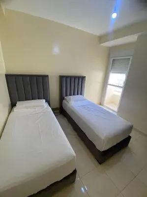 two beds in a bedroom with two windows at Well-equipped luxury apartment in Temara