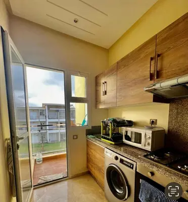 a kitchen with a washer and a microwave and a window at Appartement de vacances CASABAY Sidi Rehal in Sidi Rahal