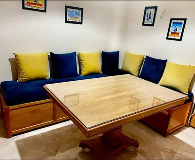 a blue couch with yellow pillows and a wooden table at Appartement de vacances CASABAY Sidi Rehal in Sidi Rahal