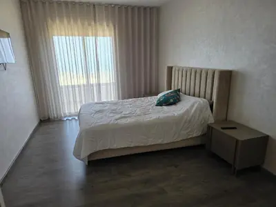 a bedroom with a bed with a pillow and a window at Duplex Zenata Tower in Aïn Harrouda