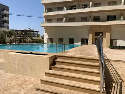 a swimming pool with stairs next to a building at Duplex Zenata Tower in Aïn Harrouda