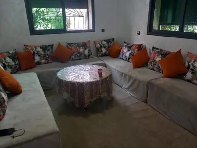 a living room with a table and couches with pillows at appartement bouznika in Bouznika