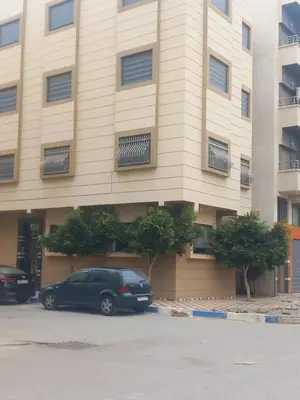 a green car parked in front of a building at appartement bouznika in Bouznika