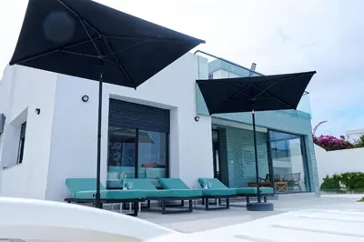 a group of chairs and umbrellas in front of a building at Villa Luxe Dar Bouazza - Piscine Privée - Fibre 100Mb - 3 min Plage in Casablanca