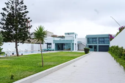 a house with a palm tree and a walkway at Villa Luxe Dar Bouazza - Piscine Privée - Fibre 100Mb - 3 min Plage in Casablanca