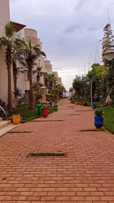 a brick walk way with palm trees and buildings at Rock Island Appartement Haut standing pied dans l'eau Mohammedia in Mohammedia