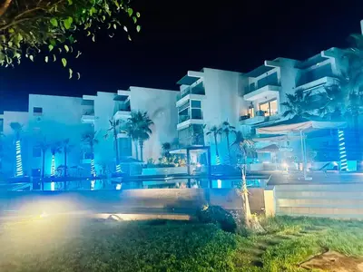 a large white building with palm trees in front of it at Rock Island Appartement Haut standing pied dans l'eau Mohammedia in Mohammedia