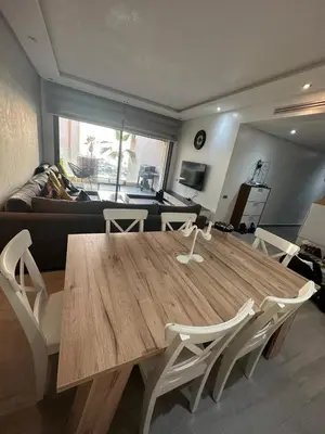 a wooden table and chairs in a living room at Rock Island Appartement Haut standing pied dans l'eau Mohammedia in Mohammedia