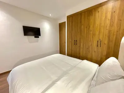 a bedroom with a white bed and a wooden cabinet at Q11 Studio au Cœur de Casablanca Proximité et Confort in Casablanca