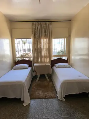 two beds in a room with two windows at Chambre cosy au cœur de Rabat in Rabat