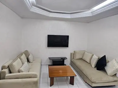 a living room with two couches and a flat screen tv at Appartement ensoleillé de 100 m2 à Mohammedia à 10 mn de la mer in Mohammedia