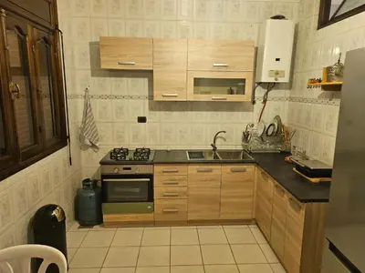 a small kitchen with wooden cabinets and a sink at Appartement ensoleillé de 100 m2 à Mohammedia à 10 mn de la mer in Mohammedia
