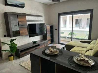 a living room with a couch and a tv at Résidence Natura Living au parc in Mohammedia