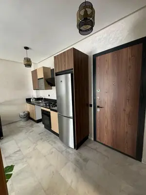 a kitchen with a stainless steel refrigerator and wooden cabinets at Résidence Natura Living au parc in Mohammedia