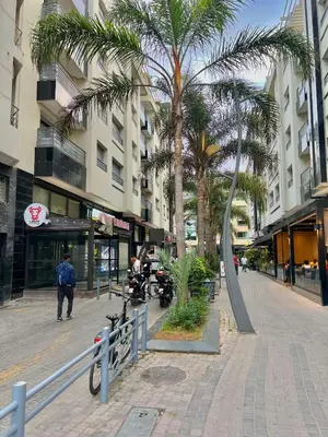 a street with palm trees and a man on a motorcycle at D2 L'Art de Vivre Urbain au Cœur de Casablanca maarif in Casablanca