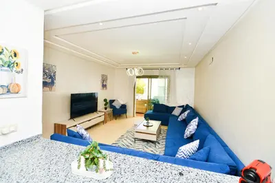 a living room with a blue couch and a tv at Modern Marina - Beach - Pool in Sidi Rahal