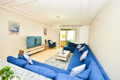 a living room with blue couches and a tv at Modern Marina - Beach - Pool in Sidi Rahal