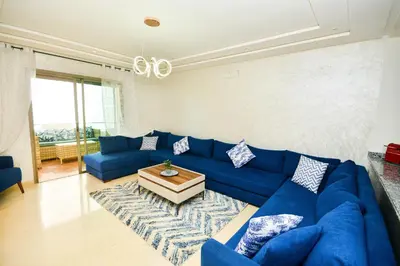 a living room with a blue couch and a table at Modern Marina - Beach - Pool in Sidi Rahal