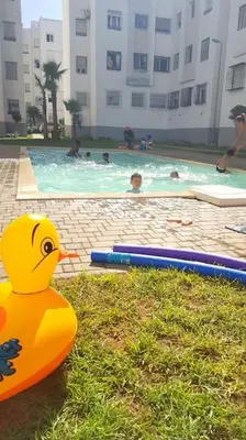 a rubber duck sitting in the grass near a swimming pool at Appartement entier Familial Tamaris-Dar Bouazza-Casablanca in Dar Bouazza