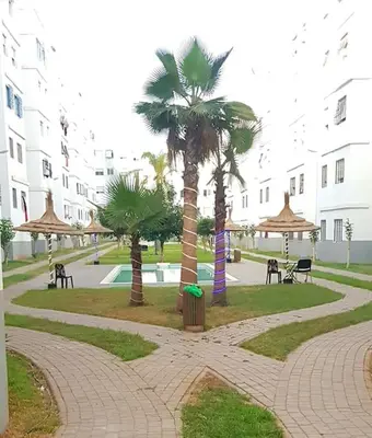 a park with palm trees and tables and umbrellas at Appartement entier Familial Tamaris-Dar Bouazza-Casablanca in Dar Bouazza