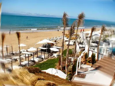 a beach with chairs and umbrellas and the ocean at Appartement entier Familial Tamaris-Dar Bouazza-Casablanca in Dar Bouazza