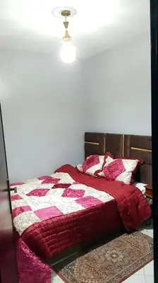 a bedroom with a bed with a red and white quilt at Appartement entier Familial Tamaris-Dar Bouazza-Casablanca in Dar Bouazza