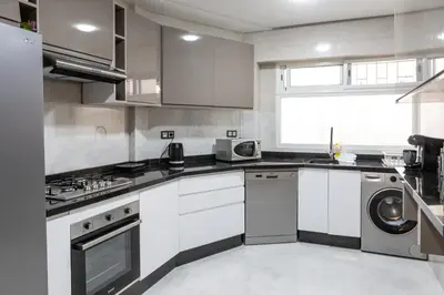 a kitchen with white cabinets and a washer and dryer at Joli appartement 2 chambres in Casablanca