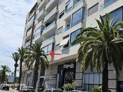 a building with palm trees in front of it at Studio a Mohammedia pied dans l'eau in Mohammedia