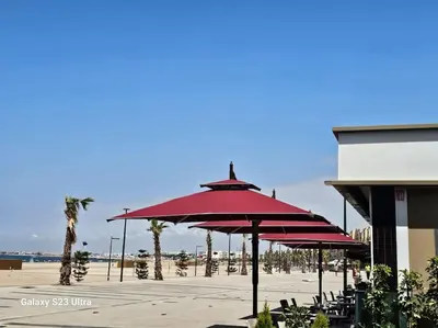a group of red umbrellas in front of a beach at Studio a Mohammedia pied dans l'eau in Mohammedia