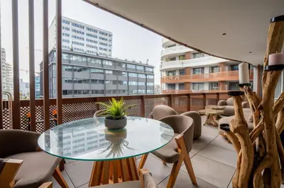 a balcony with a glass table and chairs at Élégance Urbaine Casa Finance city in LʼOasis