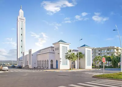 a large white building with a clock tower on a street at Résidence kettani piscine bouznika in Bouznika