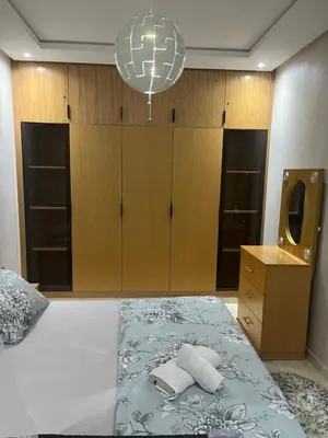 a bedroom with a bed with a dresser and a mirror at Résidence kettani piscine bouznika in Bouznika