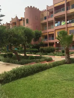 a building with trees in front of a yard at Sahara beach Mansouria in Mansouria