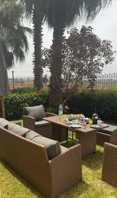 a patio with a table and chairs and palm trees at Sahara beach Mansouria in Mansouria