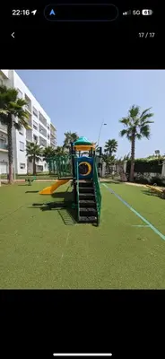 a playground with a slide in a park with palm trees at Bouznika, Shems Kettani in Bouznika
