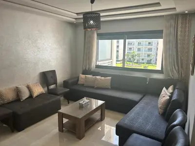 a living room with a couch and a table at Appartement location in Bouznika