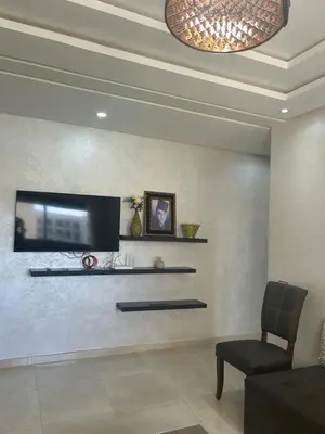 a living room with a flat screen tv on a wall at Appartement location in Bouznika