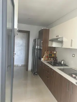 a kitchen with a refrigerator and a stove top oven at Appartement location in Bouznika
