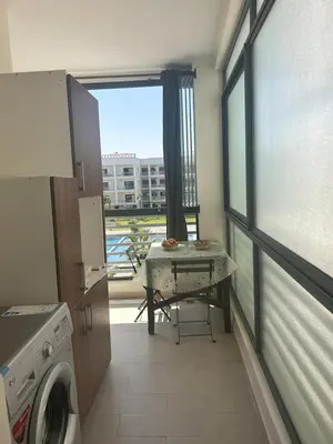 a kitchen with a table and a view of a building at Appartement location in Bouznika