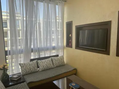 a living room with a couch in front of a window at Appartement location in Bouznika
