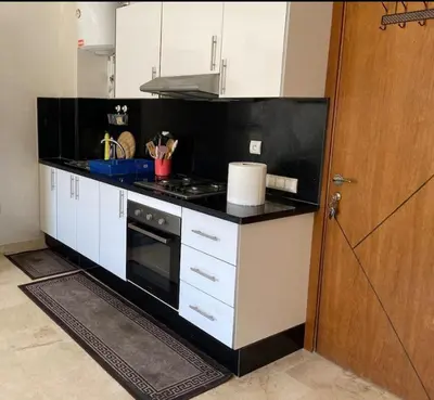 a kitchen with white cabinets and a black counter top at Studio charme à prix doux in Casablanca
