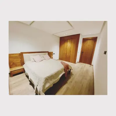 a bedroom with a bed with white sheets and wooden floors at Bostay in Casablanca