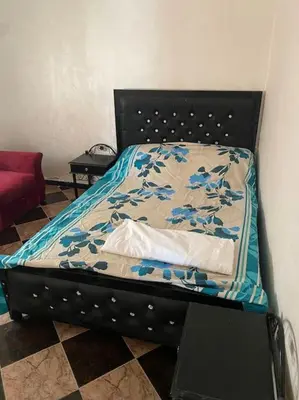 a bed with a black headboard with blue flowers on it at Villa Casablanca-Sidi Rahal à 5 min de la plage in Sidi Rahal