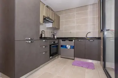a kitchen with stainless steel appliances and a purple rug at Appartement Royal in Beni Brour
