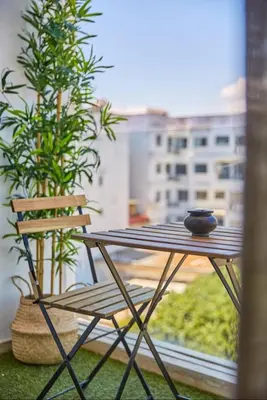 a table and a chair on a balcony with a window at Casablanca Maarif in Maarif