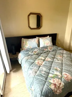 a bedroom with a bed with a floral comforter and a mirror at La perle de Tamaris in Casablanca