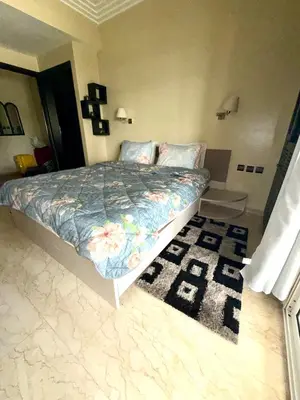a bedroom with a bed with a floral comforter and a rug at La perle de Tamaris in Casablanca