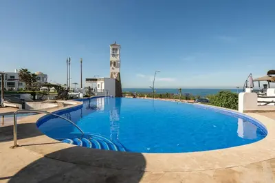 a large swimming pool with the ocean in the background at Résidence beach house in Dar Bouazza