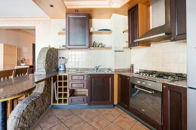 a large kitchen with wooden cabinets and counters at Résidence beach house in Dar Bouazza