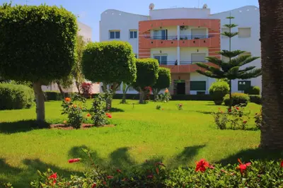 a park in front of a building with trees and flowers at Mohammedia Appartement in Mohammedia